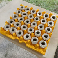 A yellow plastic, washable, resuable, 30-cell tray typically used for egg cartons filled with machine parts