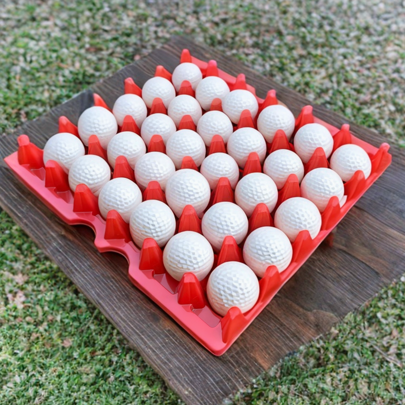 Egg Tray Filler Flat A 30-cell red plastic washable reusable egg tray, golf ball holder, golf tray, with white golf balls in each cell. Tray is on a wood plank in the grass. 