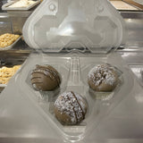 A clear plastic hear shaped 3-cell egg carton being used to hold chocolate truffles, pastry packaging, candy carton