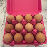 a hot pink paper pulp 12-egg carton filled with brown eggs