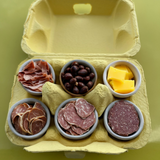 a yellow 6-egg pulp paper carton with cheese, meats, nuts instead of eggs. 