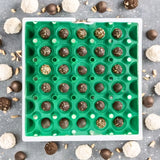A green plastic washable, stackable, reusable egg tray used to hold chocolate truffles, dessert packaging
