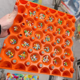 An orange plastic washable reusable stackable tray for organizing beads